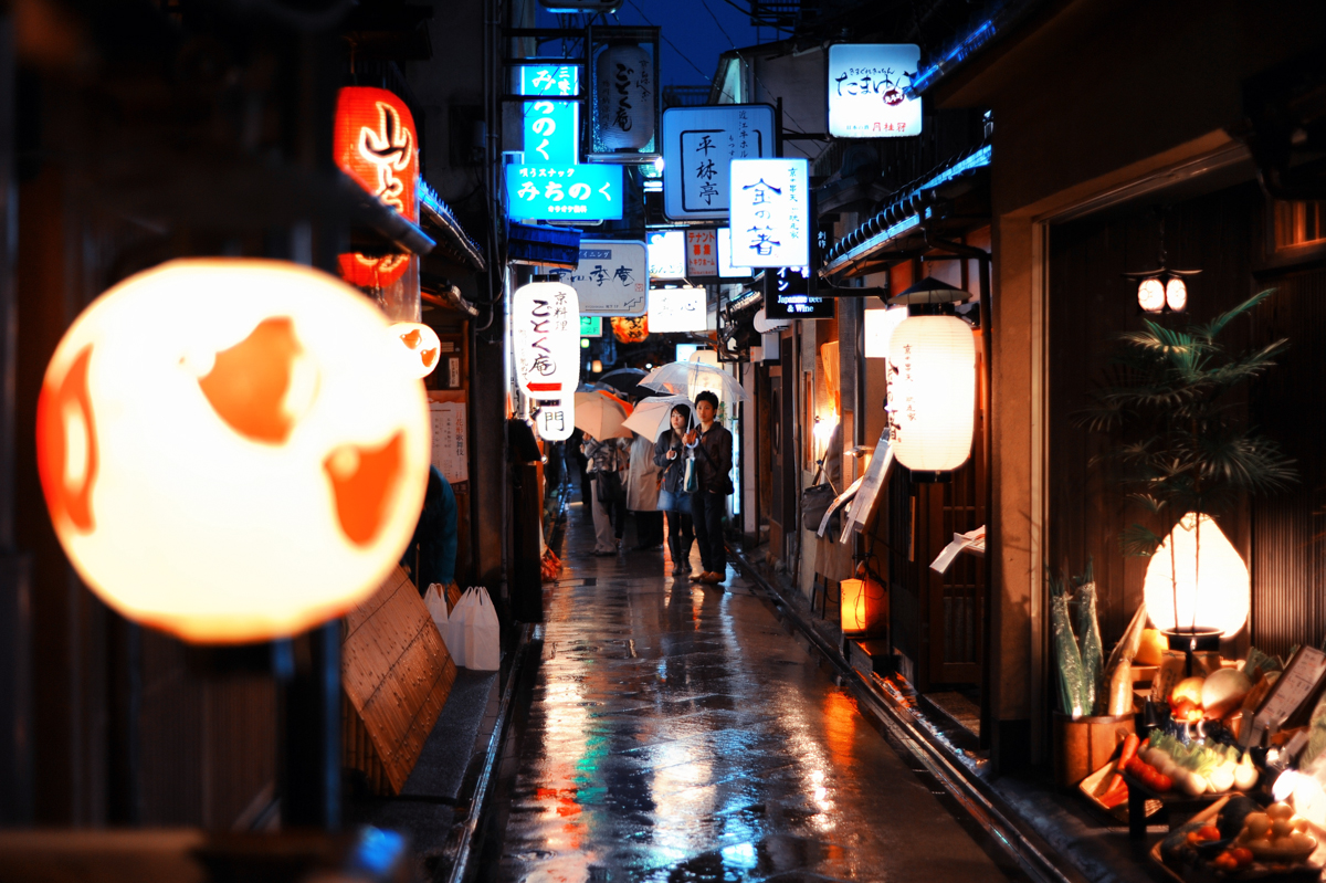 Narrow streets of historical part of Kyoto decorated with all kinds of traditional japanese lanterns at a rainy city night. Island of Honshu, Japan